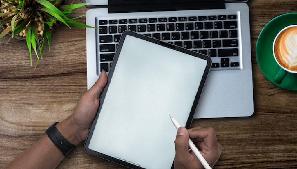 Male hands working on modern laptop. Office desktop on wooden table background.