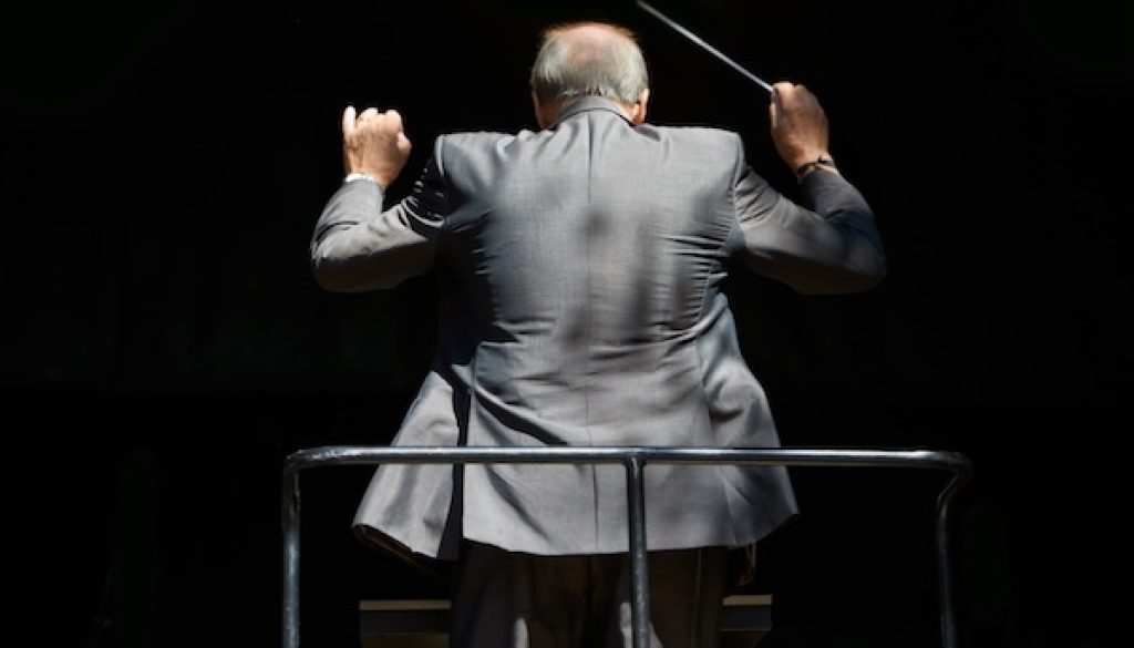 Guiding the music. Cropped rear view of an orchestra conductor waving his baton