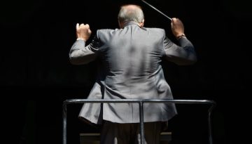 Guiding the music. Cropped rear view of an orchestra conductor waving his baton