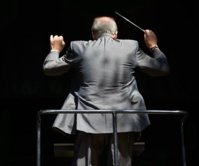 Guiding the music. Cropped rear view of an orchestra conductor waving his baton