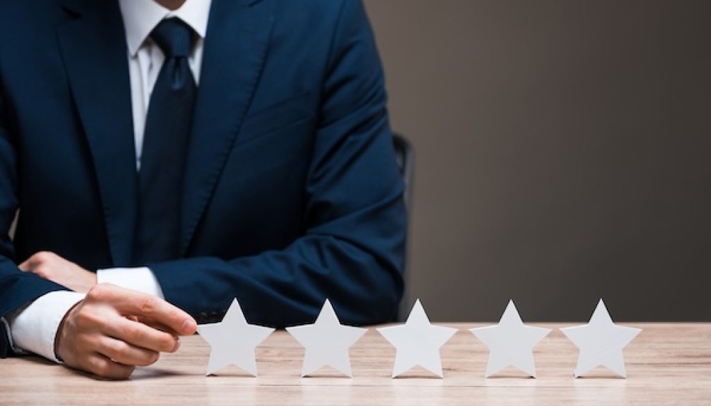 selective focus of man in suit touching star isolated on grey, quality concept