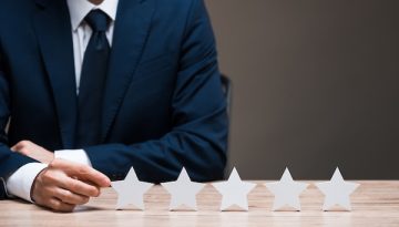 selective focus of man in suit touching star isolated on grey, quality concept