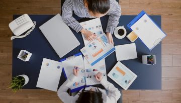 Top view of accountant women analyzing financial graphs paperwork discussing corporate expertise