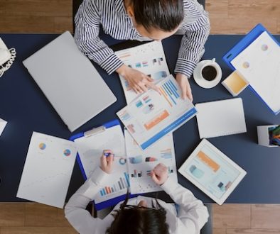 Top view of accountant women analyzing financial graphs paperwork discussing corporate expertise